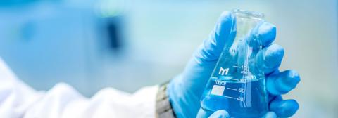 Pharmaceuticals Gloved hands holding a beaker
